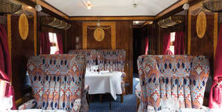 Vintage wood-panelled train carriage with liberty print chairs and formal dining tables