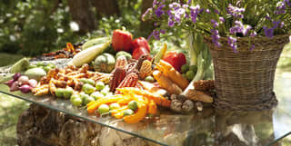 Selection of vegetables piled on a glass table with a lavender plant nearby