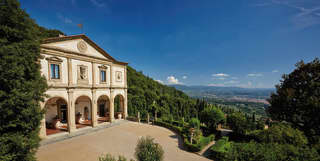 Classical exterior of a former Italian monastery with arched cloisters and a grand drive