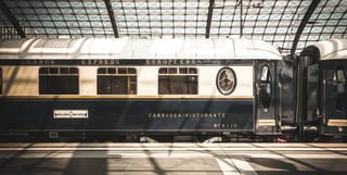 Blue and cream vintage train carriages under a glass panelled station ceiling