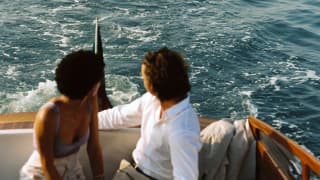 A couple looks over their shoulders at a Venetian Rowers as they take a ride across the water on the hotel’s teak launch