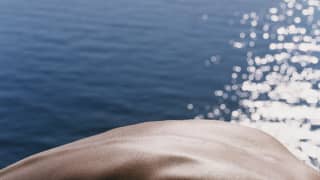 Close up shot of man's back and the sea