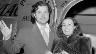 Black and white photo of American actor-director, Orson Welles and Mexican actress, Dolores del Rio, in an aeroplane doorway.