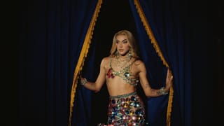 Brazilian drag queen, Pabllo Vittar poses by black velvet curtains in a beaded, upcycled glamour twin-set by Germanier.