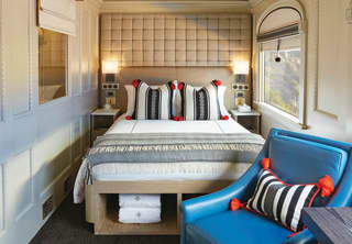 A comfortable double cabin with Peruvian-style soft furnishings, neat storage, and a blue leather armchair next to a window.