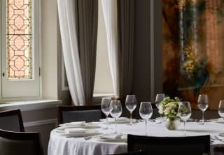 The Lillie room window spills light onto a dining table, illuminating the white tablecloth and crystal clear wineglasses.