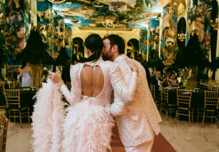 Shot from behind of a newly married couple in sharing a kiss in a glamorous room