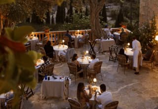 Seen from above, table lamps glow like fireflies during a magical evening on the terrace of El Olivo, circled by gardens.