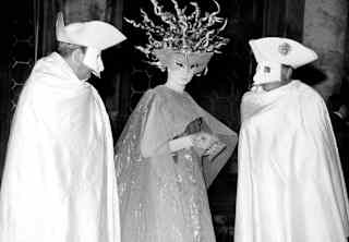 Visconti chats with Viscountess Jacqueline of Ribes and actor Franco Rosi, photographed at a costume ball in monochrome.