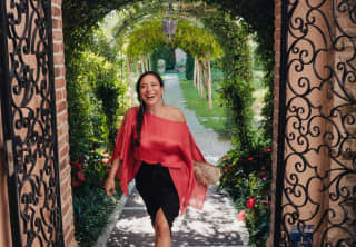 Barbara Maniacco, Guest Relations Manager, strolls from the gardens to the hotel in a red, diaphanous off-the-shoulder top.