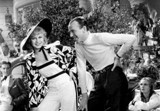 Monochrome photo of Hollywood actors, Ginger Rogers and Fred Astaire, posing together with hands on hips, theatrically.