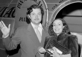 Black and white photo of American actor-director, Orson Welles and Mexican actress, Dolores del Rio, in an aeroplane doorway.