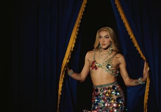 Brazilian drag queen, Pabllo Vittar poses by black velvet curtains in a beaded, upcycled glamour twin-set by Germanier.