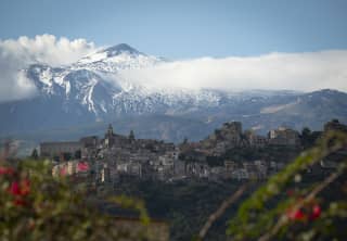 The incredible rise and snowy peak of Mount Etna looms south of Taormina's hills, seen through the lens of Gregory Halpern.