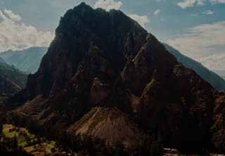 View of a rock mountain bearing down over the agricultural land by the village of Ollantaytambo in the Sacred Valley.