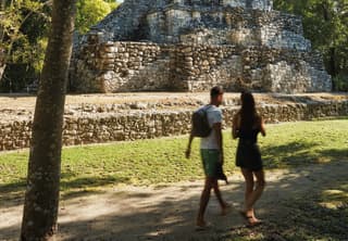 a couple walking by the Mayan ruins of Muyil