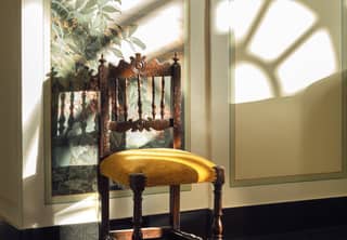 Antique chair with a mustard yellow velvet seat in a marble-floored hotel lobby