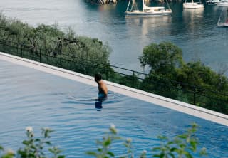 A man looks out over Portofino Bay and the immensity of the Mediterranean beyond from the edge of the hotel's pool