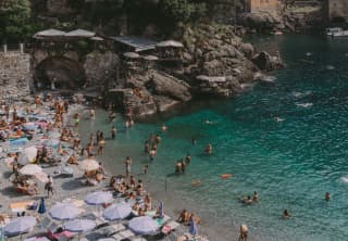 Swimmers gather in the turquoise waters of Bagni Fiore. Beach dwellers rest in the sun or shaded by lavender parasols