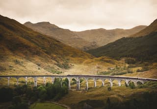 In a valley scene of plunging hillsides, the Royal Scotsman looks miniature as it crosses the span of the Glenfinnan Viaduct.