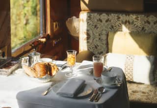 Sunlight beams through the window onto the Forest Suite table laid out with a light breakfast of bread and juice.