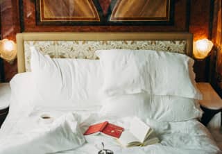 In La Foret, open books and a breakfast tray rest on the white linen of an unmade bed, nestled in the rich wooden surrounds.