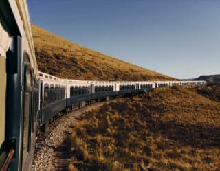 Row of the Andean Explorer carriages crossing the plains trackside