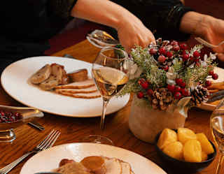A guest spoons a helping of Brussel sprouts on to her plate of turkey and stuffing as her companion reaches for a side-dish.