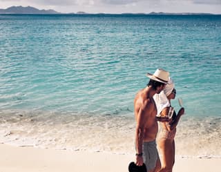 A couple in swimsuits taking a stroll along the tranquil shoreline of Maundays Bay