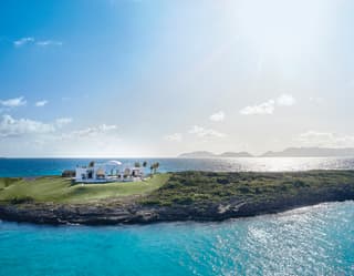 Domed villa on a grassy peninsula under blue skies