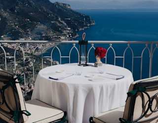 A dining table with an ornament by local artist, Sandulli, enjoys plunging views of the coast from the restaurant terrace.