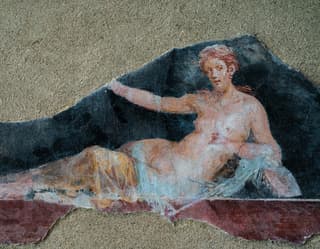 Close-up of a broken wall fresco of a nude red-haired lady reclining under a veil