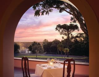 A private candlelit table for two on a balcony overlooking tropical gardens