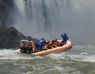 An orange speed raft with guests on board approaching the Iguassu Falls