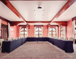 Large pink room with conference tables in a U-formation