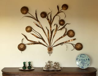 Living room detail of a rustic-style Italian mid-century wall lamp with gilded metal ribbons shaped to look like wheat.