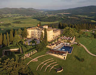 Behind the steps of an ancient Etruscan amphitheatre, the pale yellow walls of the hotel stand tall amid extensive gardens