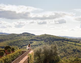 A woman leans on the terrace balcony railings, as if on the deck of a ship, soaking in the uninterrupted views of lush hills