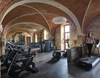 A redbrick vaulted ceiling arches high above a well-equipped gym with treadmills, static bikes, cross-trainer and weights