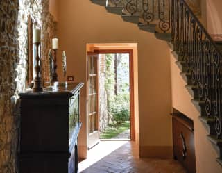 Blush-coloured stairwell with an open door leading to sunlit gardens