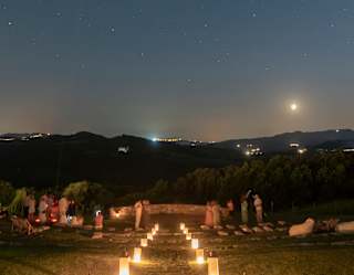 On a dark night with the moon hanging low, candle lanterns light the steps down to the ancient Etruscan amphitheatre.
