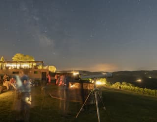 Telescopes are set up and guests mingle in the night air by lamp light during a stargazing experience at Castello di Casole.
