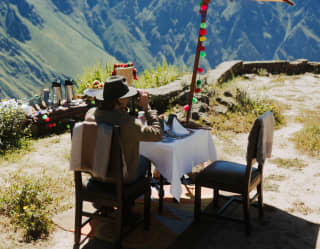 a lady sitting at al fresco breakfast table looking at view of Colca Canyon