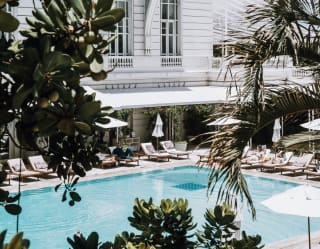 Palm and lime trees give dark green relief to the stark white walls of the hotel's facade and the pale azure rectangle of the pool