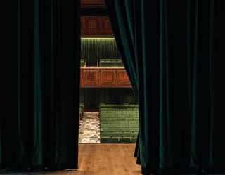 Peering through a gap in the green velvet curtains we can see from the stage to the stalls, wood panelling and green seating