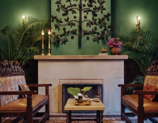 Green room with tan leather sofas either side of a large stone fireplace