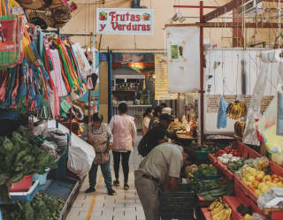 View of the entrance to the Ignacio Ramírez Market, where stalls sell bright baskets and woven goods alongside fresh produce.