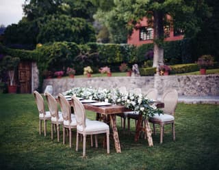 Outdoor banquet table in a garden with a full-length lily centrepiece