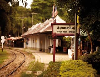 Colonial-style platform with a River Kwai Bridge station sign in Thai and English