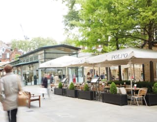 People walk past Polpo restaurant's al-fresco setting in Chelsea's Duke of York Square, near The Cadogan Hotel.